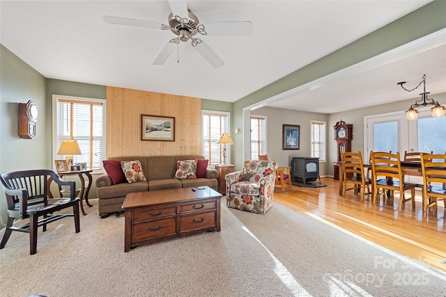 living room with ceiling fan, plenty of natural light, and a wood stove