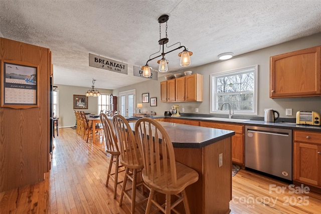 kitchen with dishwasher, decorative light fixtures, sink, a center island, and a breakfast bar area