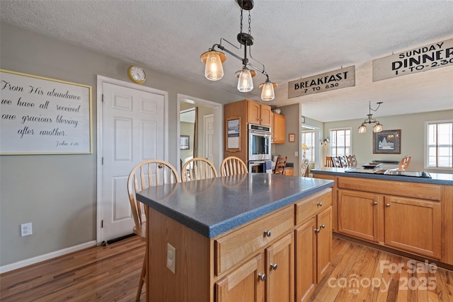 kitchen with pendant lighting, double oven, light hardwood / wood-style flooring, and a kitchen island