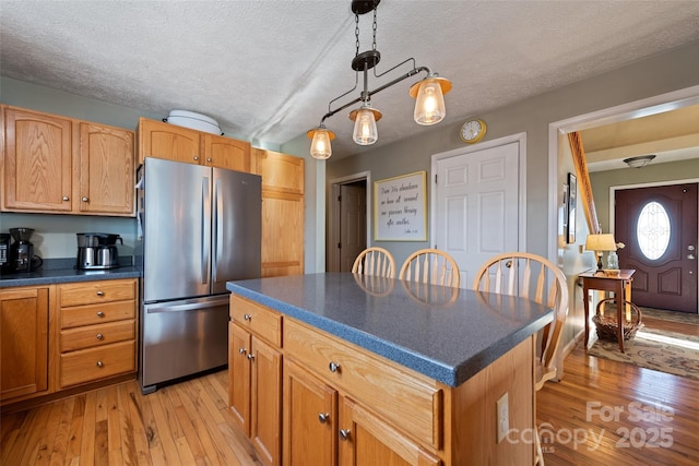 kitchen featuring a center island, stainless steel refrigerator, pendant lighting, and a textured ceiling