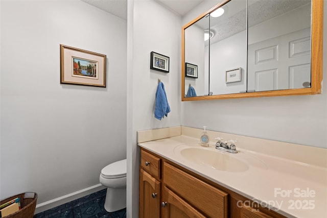 bathroom featuring a textured ceiling, toilet, and vanity