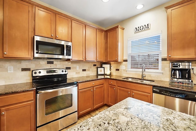 kitchen featuring backsplash, appliances with stainless steel finishes, sink, and dark stone countertops