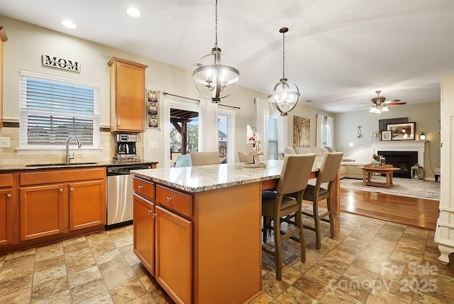 kitchen with a kitchen island, dishwasher, sink, a kitchen breakfast bar, and hanging light fixtures