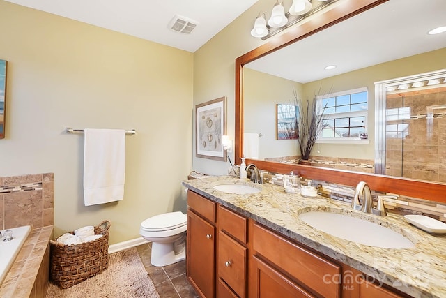 bathroom with tile patterned flooring, vanity, tiled bath, and toilet