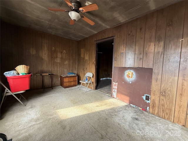 spare room with ceiling fan, light carpet, and wood walls