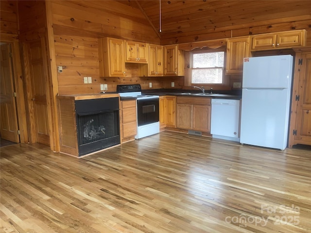 kitchen with sink, wood walls, vaulted ceiling, light hardwood / wood-style flooring, and white appliances