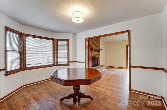 unfurnished office with a textured ceiling, a brick fireplace, and light wood-type flooring