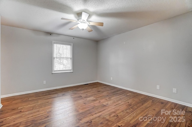 spare room featuring a textured ceiling, dark wood-type flooring, and ceiling fan