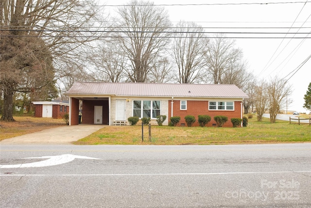 ranch-style home featuring metal roof, brick siding, concrete driveway, a carport, and a front lawn