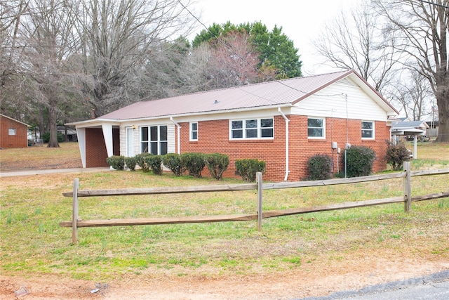 ranch-style house featuring metal roof, brick siding, fence, and a front lawn