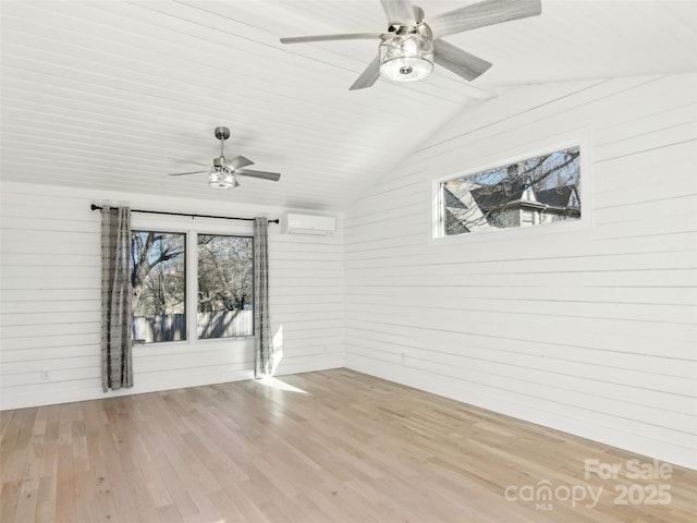 unfurnished room with light wood-type flooring, a wall unit AC, lofted ceiling, and ceiling fan