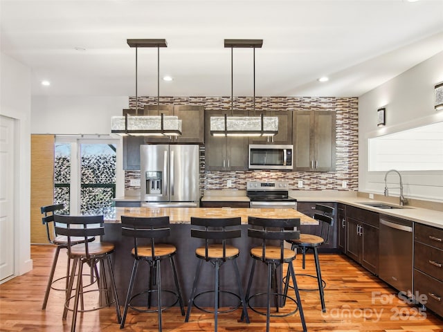 kitchen featuring hanging light fixtures, appliances with stainless steel finishes, sink, and a kitchen island