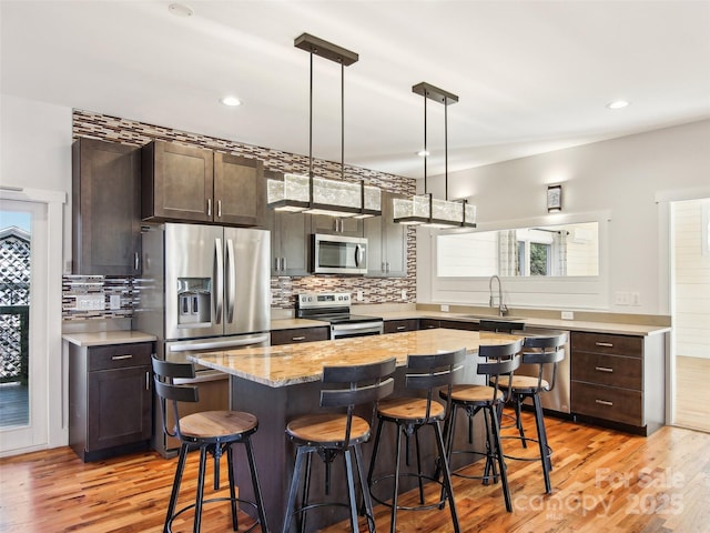 kitchen featuring a kitchen breakfast bar, stainless steel appliances, dark brown cabinetry, and a center island