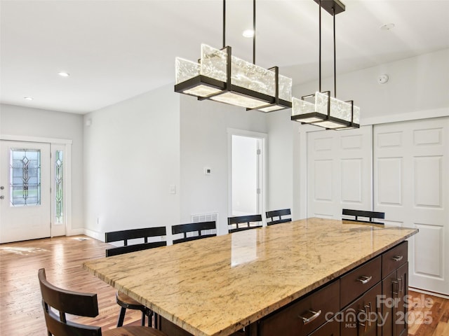 kitchen featuring light hardwood / wood-style flooring, hanging light fixtures, a center island, and dark brown cabinets