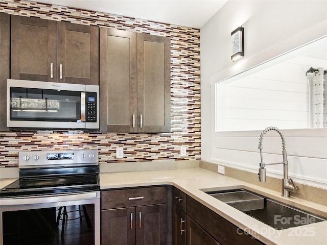 kitchen with sink, stainless steel appliances, decorative backsplash, and dark brown cabinetry