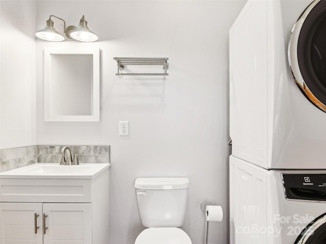 bathroom with vanity, stacked washer / drying machine, and toilet