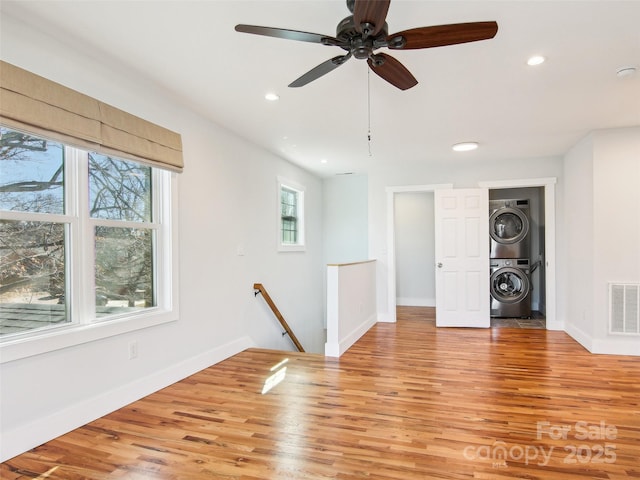 unfurnished room featuring light wood-type flooring and stacked washer / drying machine