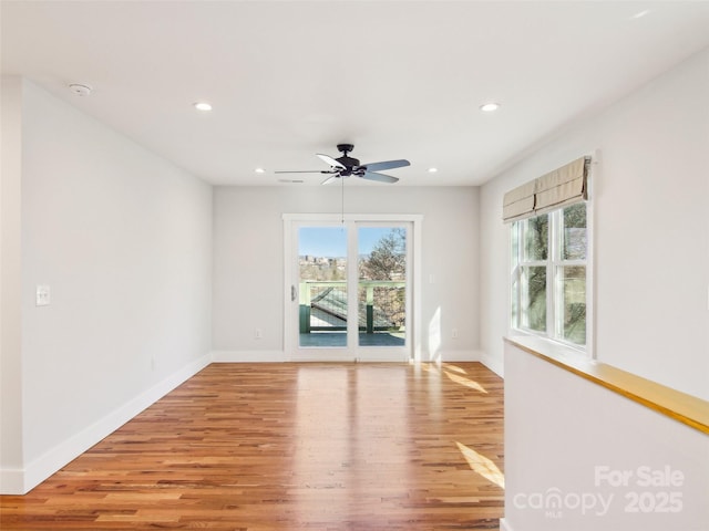 empty room featuring a healthy amount of sunlight, light hardwood / wood-style flooring, and ceiling fan