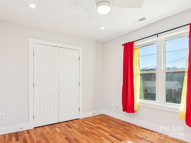 unfurnished bedroom featuring a closet, hardwood / wood-style flooring, and ceiling fan