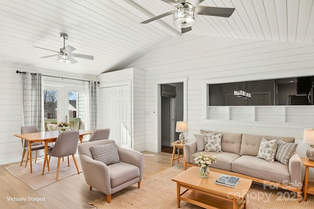 living room with ceiling fan, light hardwood / wood-style flooring, vaulted ceiling with beams, and wood walls