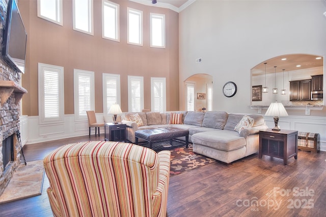 living room with dark wood-type flooring, a healthy amount of sunlight, a fireplace, and crown molding