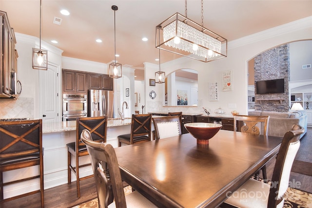 dining room with visible vents, arched walkways, ornamental molding, wood finished floors, and recessed lighting