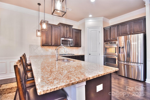 kitchen featuring dark brown cabinets, stainless steel appliances, a sink, and a kitchen breakfast bar