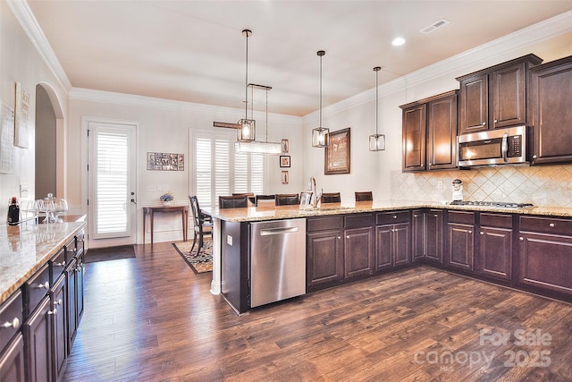 kitchen featuring stainless steel appliances, a peninsula, a sink, visible vents, and dark wood finished floors