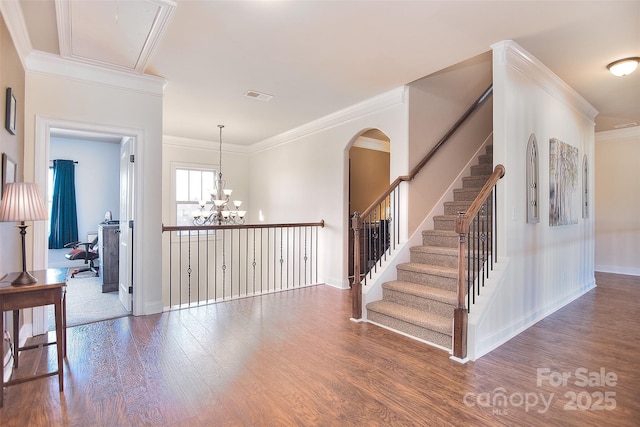 interior space featuring attic access, visible vents, wood finished floors, crown molding, and a notable chandelier