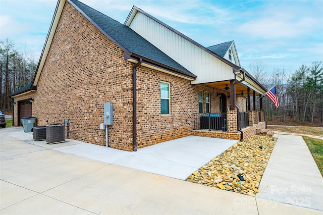 view of side of home featuring covered porch, a garage, and central AC