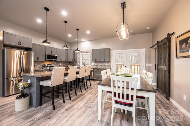 dining area with french doors, a barn door, and light hardwood / wood-style floors