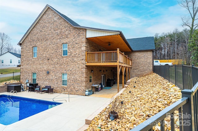 rear view of property with a fenced in pool, a balcony, and a patio area