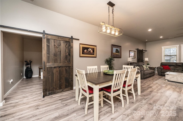 dining area featuring a barn door and light hardwood / wood-style flooring