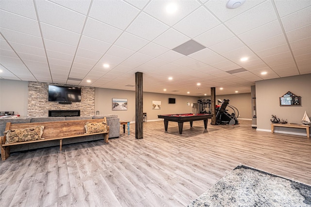 recreation room featuring a stone fireplace, hardwood / wood-style floors, a drop ceiling, and billiards