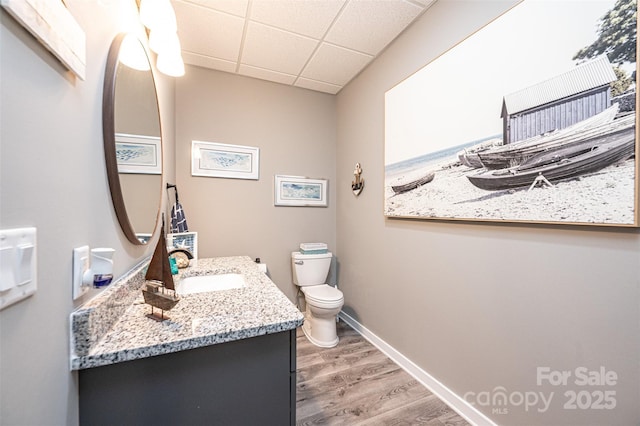 bathroom with hardwood / wood-style flooring, vanity, a paneled ceiling, and toilet