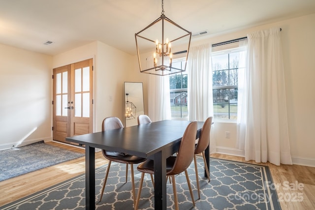 dining area with a chandelier, hardwood / wood-style flooring, and french doors