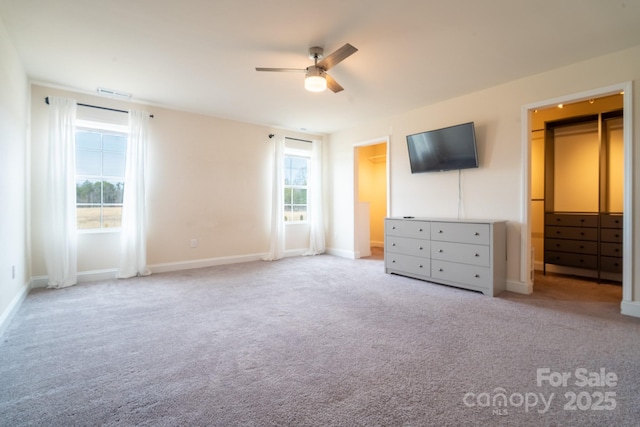 unfurnished bedroom featuring a spacious closet, ceiling fan, and light colored carpet