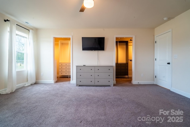 unfurnished bedroom with a closet, a spacious closet, light carpet, and ceiling fan