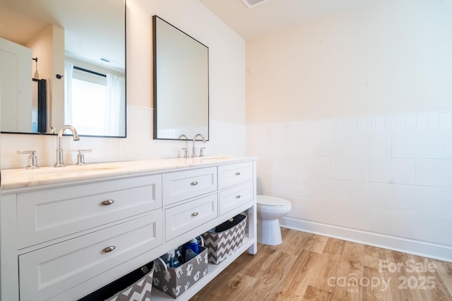 bathroom with toilet, tile walls, hardwood / wood-style floors, and vanity