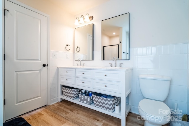 full bathroom featuring a sink, a wainscoted wall, tile walls, double vanity, and wood finished floors