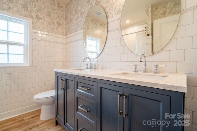 bathroom with toilet, tile walls, hardwood / wood-style flooring, and vanity