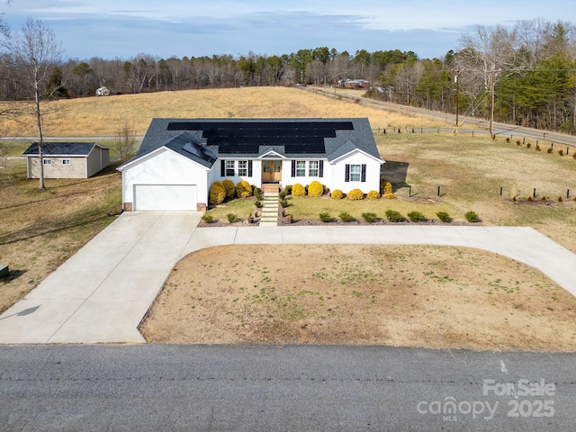 view of front facade with a front lawn, solar panels, a garage, and a rural view