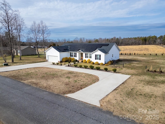 single story home with a front lawn, solar panels, a garage, and a rural view