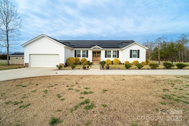 ranch-style home featuring roof mounted solar panels, driveway, a front lawn, and a garage