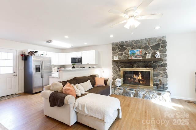 living room with a fireplace, light hardwood / wood-style floors, and ceiling fan