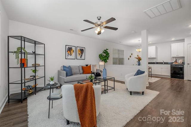 living room with dark hardwood / wood-style flooring, sink, and ceiling fan