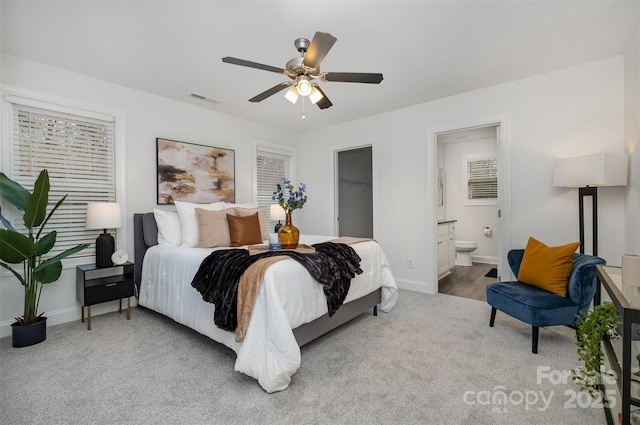 carpeted bedroom with a walk in closet, connected bathroom, ceiling fan, and a closet