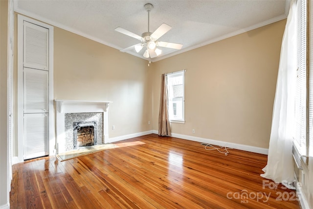 unfurnished living room with ceiling fan, ornamental molding, hardwood / wood-style floors, and a textured ceiling