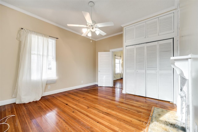 unfurnished bedroom featuring hardwood / wood-style flooring, crown molding, ceiling fan, and a closet