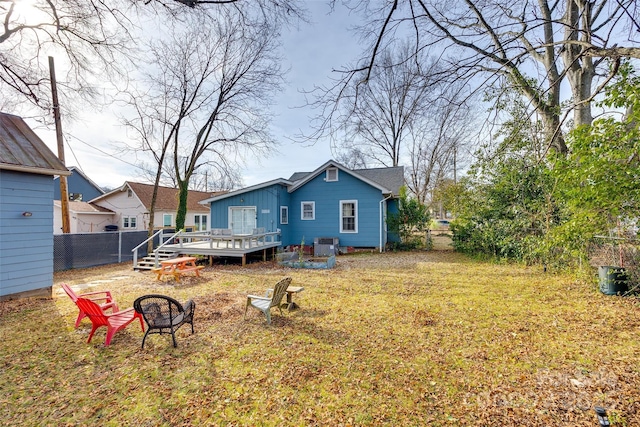 back of house featuring a wooden deck, a lawn, and an outdoor fire pit